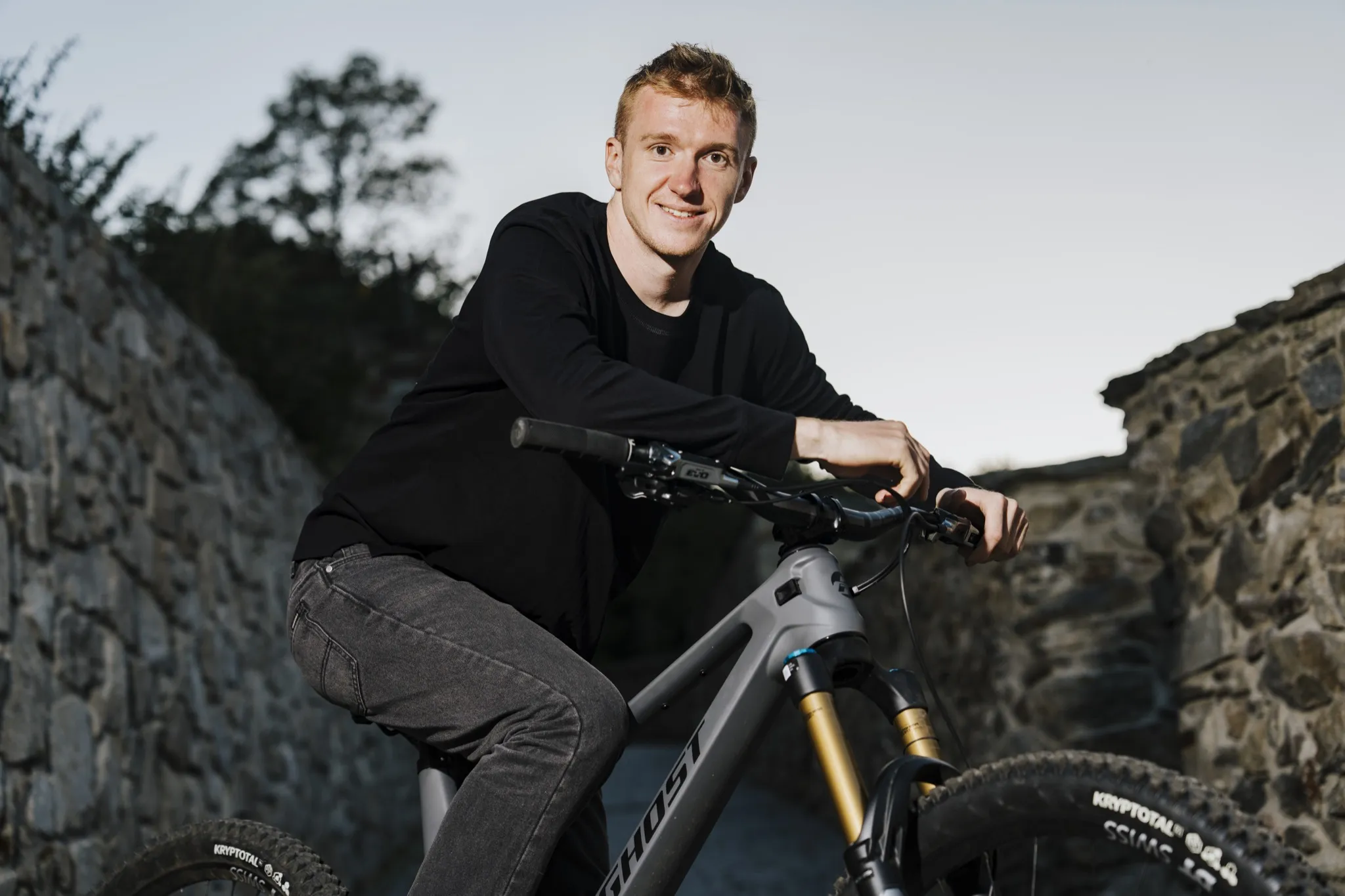 Tomáš Král se usmívá na kole Ghost, opřený o řídítka